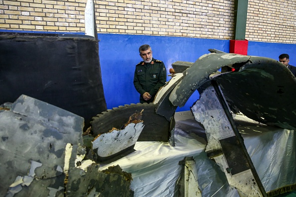 General Amir Ali Hajizadeh (C), Iran's Head of the Revolutionary Guard's aerospace division, looks at debris from a downed US drone reportedly recovered within Iran's territorial waters and put on display by the Revolutionary Guard in the capital Tehran on June 21, 2019. - Iran's state television broadcast images of what it said was debris from a downed US drone recovered inside its territorial waters. The television broadcast a short clip of a Revolutionary Guards general answering questions in front of some of the debris he said had been recovered after yesterday's missile strike. The downing of the drone -- which Washington insists was over international waters but Tehran says was within its airspace -- has seen tensions between the two countries spike further after a series of attacks on tankers the US has blamed on Iran. (Photo by Meghdad Madadi / TASNIM NEWS / AFP) (Photo credit should read MEGHDAD MADADI/AFP/Getty Images)