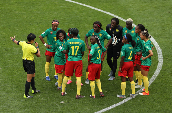 VALENCIENNES, FRANCE - JUNE 23: Players of Cameroon argue with referee Qin Liang following England's second goal during the 2019 FIFA Women's World Cup France Round Of 16 match between England and Cameroon at Stade du Hainaut on June 23, 2019 in Valenciennes, France. (Photo by Robert Cianflone/Getty Images)