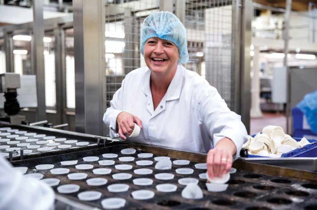 A Finsbury Food worker laughs as they prepare cupcakes in a factory (Main image credit: Finsbury Food)