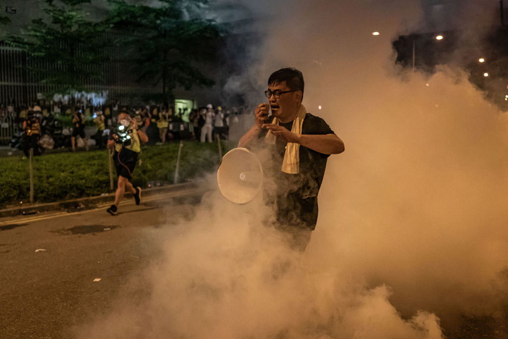 HONG KONG, HONG KONG - JULY 2: A protester reacts after police fire tear gas outside the Legislative Council Complex on July 2, 2019 in Hong Kong, China. Thousands of pro-democracy protesters faced off with riot police on Monday during the 22nd anniversary of Hong Kong's return to Chinese rule as riot police officers used batons and pepper spray to push back demonstrators. The city's embattled leader Carrie Lam watched a flag-raising ceremony on a video display from inside a convention centre, citing bad weather, as water-filled barricades were set up around the exhibition centre. (Photo by Anthony Kwan/Getty Images)