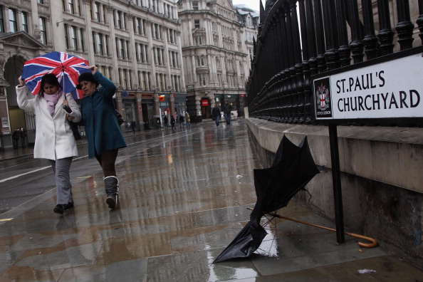 LONDON, UNITED KINGDOM - JANUARY 03:  Two women taking shelter under a Union Jack umbrella walk past a discarded broken one as they walk in the pouring rain outside St Paul's Cathedral on January 3, 2012 in London, United Kingdom. Much of the UK has encountered wet and fiercely windy weather as people return to work after the Christmas period.  (Photo by Dan Kitwood/Getty Images)