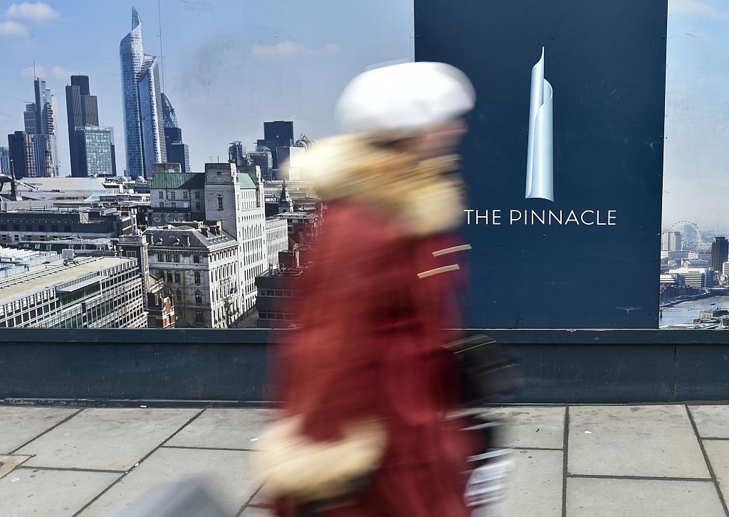 A woman walks past the construction site of the partially built 'The Pinnalce' skyscraper in Bishopsgate, London on February 22, 2015. French real estate consortium Axa Real Estate has clinched a GBP 300m deal (about 406 080 000 euros) to buy the site near Liverpool Street station in the city's Square Mile. Since construction stopped three years ago, the building has become known as the Stump.  AFP PHOTO / NIKLAS HALLE'N        (Photo credit should read NIKLAS HALLE'N/AFP/Getty Images)