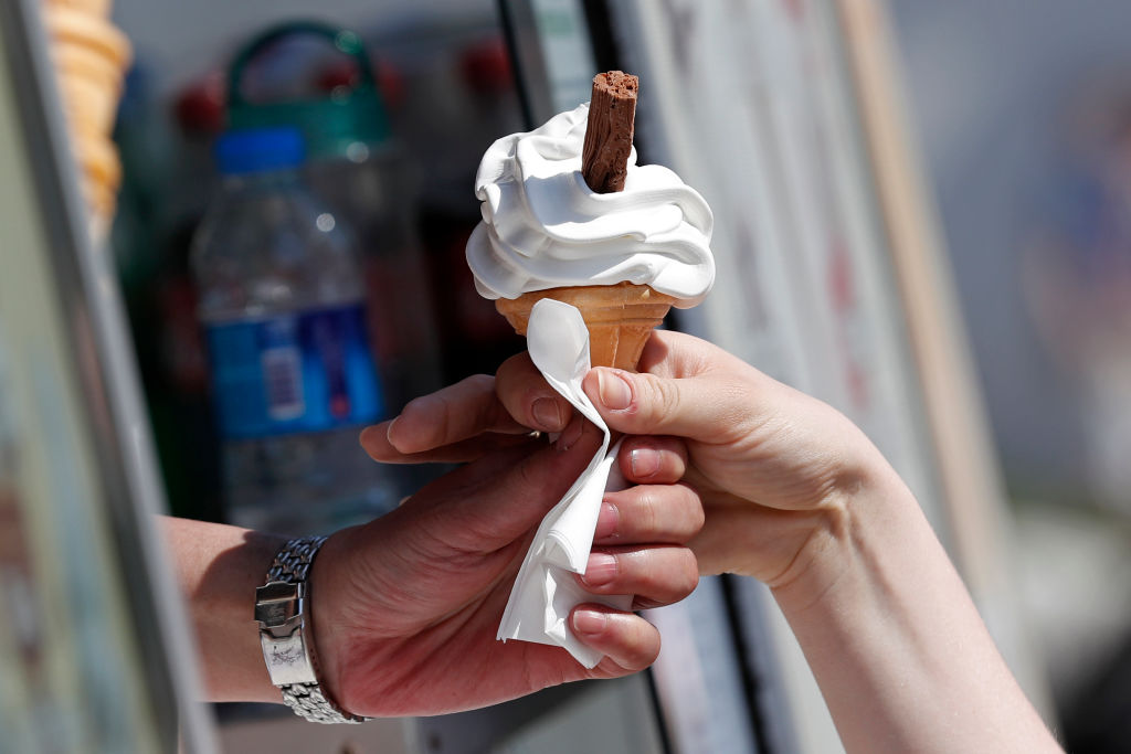 A customer (R) takes a "99" ice cream from a vendor as people enjoy the hot weather in Richmond, south west London on May 7, 2018. - Temperatures on Monday were predicted to reach 29C (84.2F) in parts of the south east of England, as people enjoyed the three-day bank holiday weekend. (Photo by Adrian DENNIS / AFP)        (Photo credit should read ADRIAN DENNIS/AFP/Getty Images)