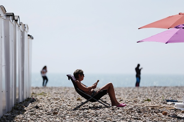 A woman sits on the beach in a deck chair reading on a sunny day in Le Havre, northwestern France, on May 27, 2016.  / AFP / CHARLY TRIBALLEAU        (Photo credit should read CHARLY TRIBALLEAU/AFP/Getty Images)