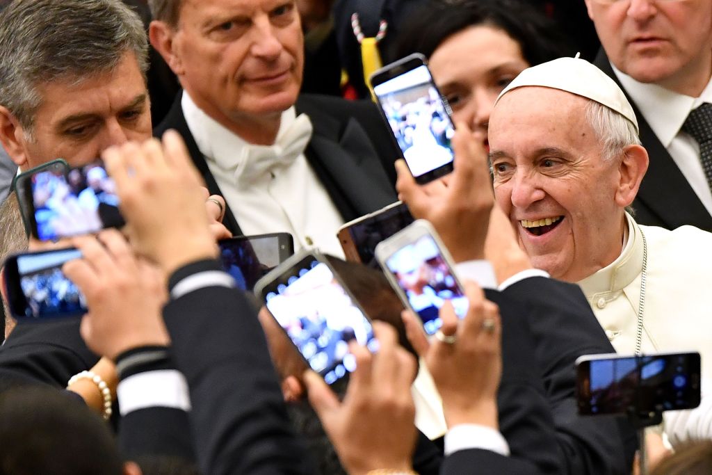 TOPSHOT - Pope Francis (R) arrives to lead his weekly general audience at Paul VI hall on December 21, 2016 at the Vatican as people take pictures of him with their cell-phone. / AFP PHOTO / Alberto PIZZOLI        (Photo credit should read ALBERTO PIZZOLI/AFP/Getty Images)