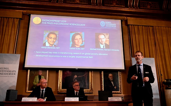 Peter Fredriksson (L), chairman of the Economic Sciences Prize Committee 2019, and the Royal Swedish Academy of Sciences' secretary general Goran Hansson (2nd L) listen to Jakob Svensson (R), member of the Economic Sciences Prize Committee 2019, as he explains the field of work of the co-winners of the 2019 Sveriges Riksbank Prize in Economic Sciences in Memory of Alfred Nobel (on the screen, L-R:  Abhijit Banerjee, Esther Duflo and Michael Kremer) during a press conference at the Royal Swedish Academy of Sciences in Stockholm, Sweden, on October 14, 2019. - Indian-born Abhijit Banerjee of the US, French-American Esther Duflo and Michael Kremer of the US won the Nobel Economics Prize for their "experimental approach to alleviating global poverty", the Royal Swedish Academy of Sciences said. (Photo by Jonathan NACKSTRAND / AFP) (Photo by JONATHAN NACKSTRAND/AFP via Getty Images)
