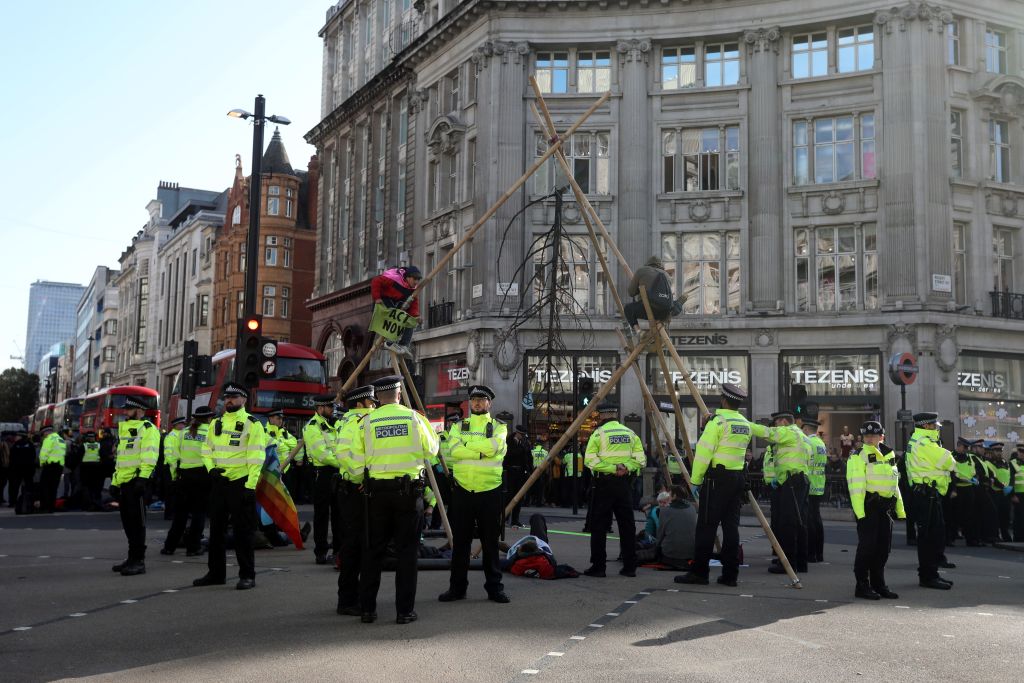 Police monitor as climate activists perch on a make-shift structure in Oxford Street during the twelfth day of demonstrations by the climate change action group Extinction Rebellion, in London, on October 18, 2019. - The Extinction Rebellion pressure group has been staging 10 days of colourful but disruptive action across London and other global cities to draw attention to climate change. (Photo by ISABEL INFANTES / AFP) (Photo by ISABEL INFANTES/AFP via Getty Images)
