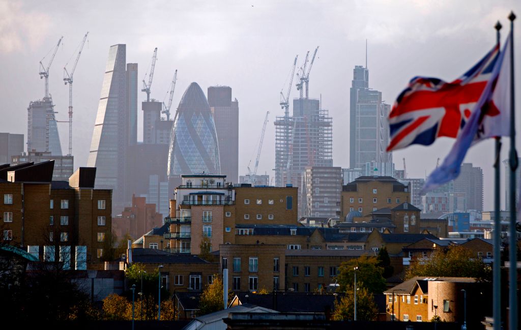 A Union flag flies from a pole as construction cranes stand near skyscrapers in the City of London, including the Heron Tower, Tower 42, 30 St Mary Axe commonly called the "Gherkin", the Leadenhall Building, commonly called the "Cheesegrater", as they are pictured beyond blocks of residential flats and apartment blocks, from east London on October 21, 2017. / AFP PHOTO / Tolga AKMEN        (Photo credit should read TOLGA AKMEN/AFP/Getty Images)