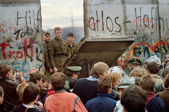West Berliners crowd in front of the Berlin Wall early 11 November 1989 as they watch East German border guards demolishing a section of the wall in order to open a new crossing point between East and West Berlin, near the Potsdamer Square. Two days before, Gunter Schabowski, the East Berlin Communist party boss, declared that starting from midnight, East Germans would be free to leave the country, without permission, at any point along the border, including the crossing-points through the Wall in Berlin. The Berlin concrete wall was built by the East German government in August 1961 to seal off East Berlin from the part of the city occupied by the three main Western powers to prevent mass illegal immigration to the West. According to the "August 13 Association" which specialises in the history of the Berlin Wall, at least 938 people - 255 in Berlin alone - died, shot by East German border guards, attempting to flee to West Berlin or West Germany. (Photo by GERARD MALIE / AFP)        (Photo credit should read GERARD MALIE/AFP via Getty Images)