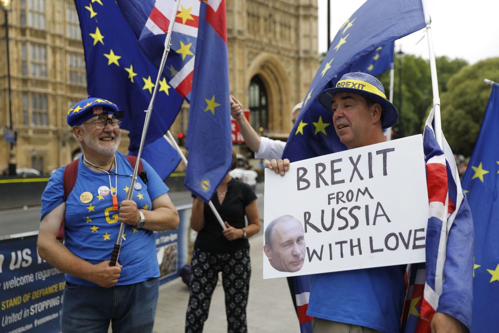 Anti-Brexit protester Steve Bray (R) holds a placard showing the face of Russian President Vladimir Putin as he protests with an EU flag against Britain's exit from the European Union outside the Houses of Parliament in London on July 4, 2018. (Photo by Tolga AKMEN / AFP)        (Photo credit should read TOLGA AKMEN/AFP via Getty Images)