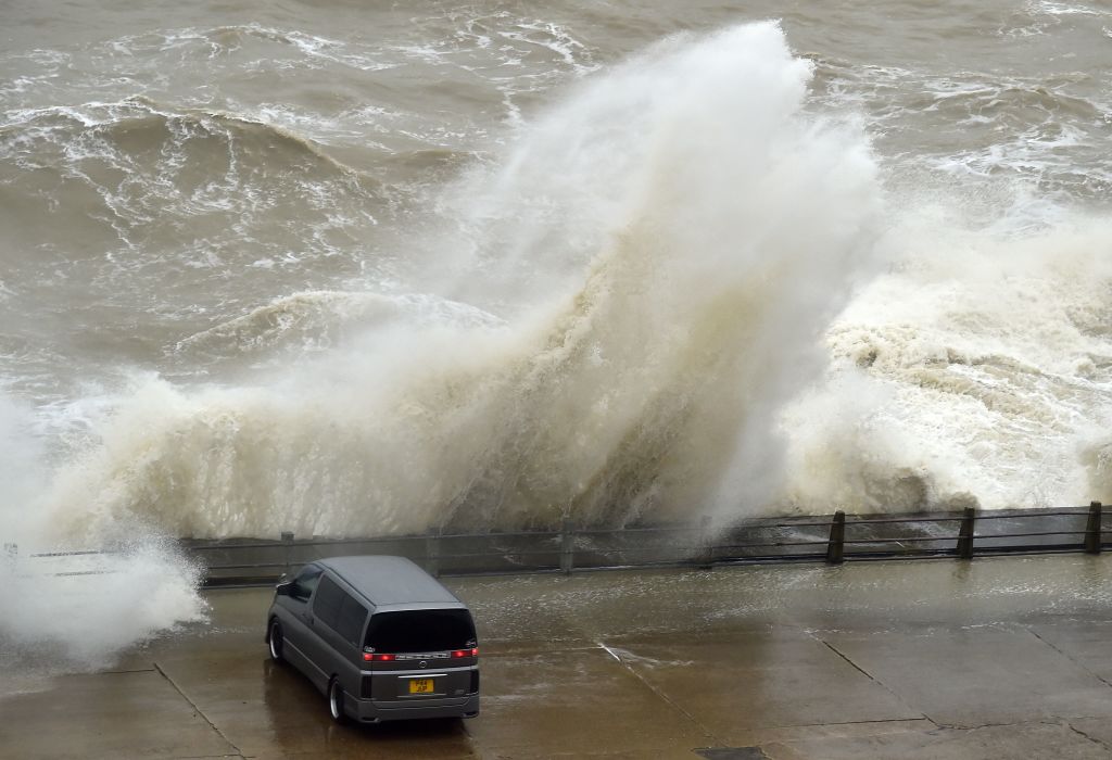 People sit in their cars to watch as Storm Ciara causes waves to crash over the wall at Newhaven Harbour on the south coast of England