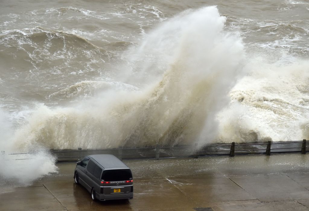 People sit in their cars to watch as Storm Eunice causes waves to crash over the wall at Newhaven Harbour on the south coast of England