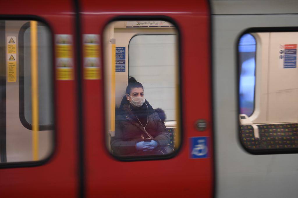 A commuter wears a mask as she travels on the tube in London