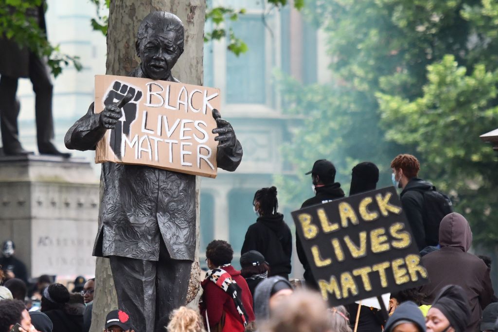A statue of former South African president Nelson Mandela is seen holding a Black Lives Matter placard in Parliament Square, central London. It has been boarded up to protect it from demonstrations