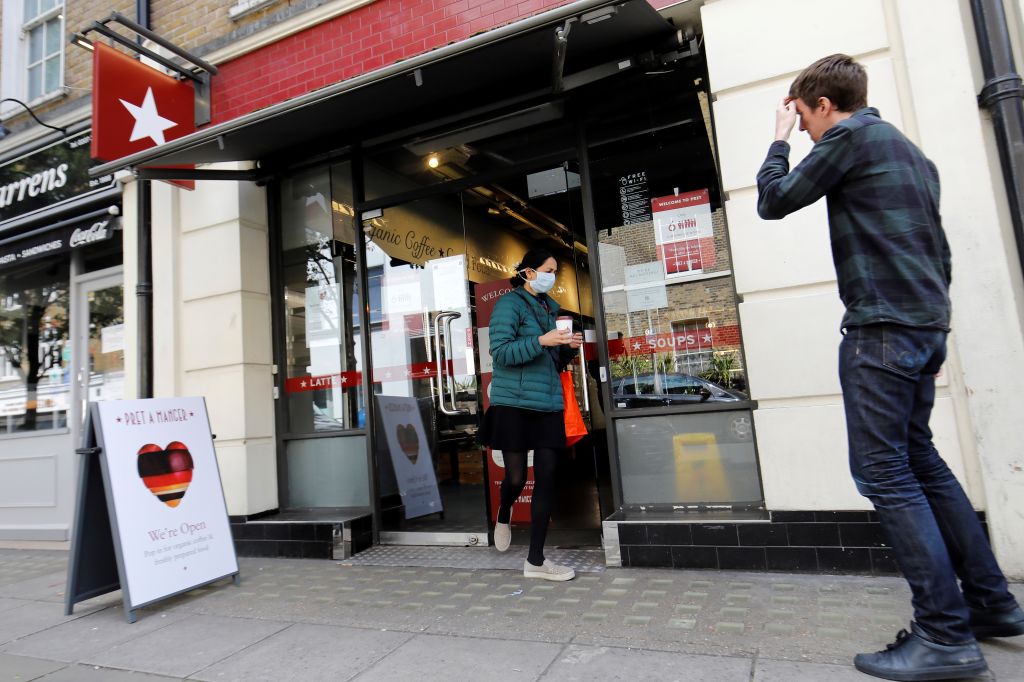 A customer carries a drink as she leaves from a recently re-opened Pret A Manger shop