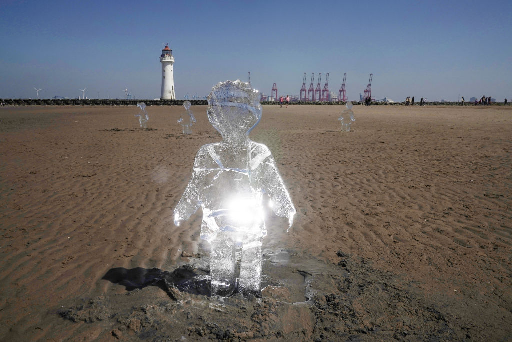 Some of 26 ice sculptures of children installed on New Brighton Beach begin to melt, as part of a giant sand artwork to highlight global warming and the forthcoming COP26 global climate conference in May 31, in Wirral, Merseyside. (Photo by Christopher Furlong/Getty Images)