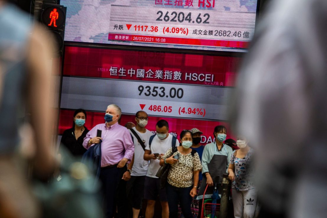 People stand in front of an electronic display showing the Hang Seng Index in the Central district of Hong Kong (ISAAC LAWRENCE / AFP) (Photo by ISAAC LAWRENCE/AFP via Getty Images)