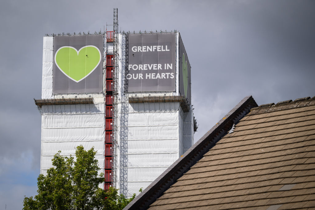 LONDON, ENGLAND - MAY 12: The covered structure of Grenfell Tower is seen above a nearby housing estate on May 12, 2021 in London, England. The Ministry of Housing Communities and Local Government (MHCLG) has announced that it is considering demolishing the building, but that it will be at least a year before any decision on the future of the tower is implemented. 72 people lost their lives in a blaze at the tower block in west London in June 2017. (Photo by Leon Neal/Getty Images)