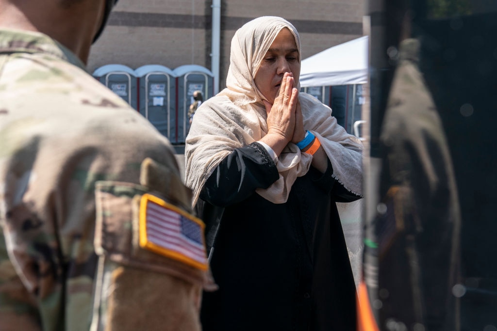 A woman prays as she boards a bus at a processing center for refugees evacuated from Afghanistan at the Dulles Expo Center in Chantilly, Virginia. (Photo by Joshua Roberts/Getty Images)