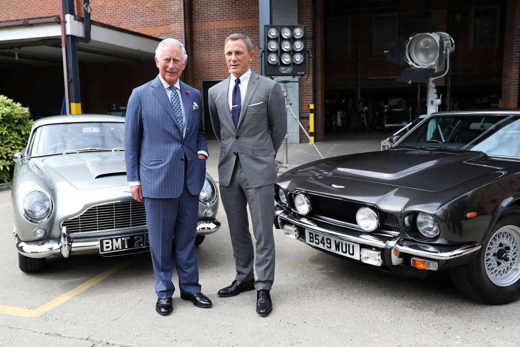 Prince Charles, Prince of Wales and actor Daniel Craig  pose with Aston Martin models during a visit to the James Bond set at Pinewood Studios in 2019 (Source: Getty)