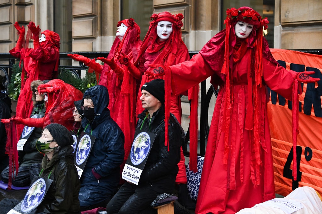 Red Rebels join protesters from Extinction Rebellion for a "die in" outside the offices of American asset management firm Mercer on November 08, 2021 in Glasgow, Scotland. As World Leaders meet to discuss climate change at the COP26 Summit, many climate action groups have taken to the streets to protest for real progress to be made by governments to reduce carbon emissions, clean up the oceans, reduce fossil fuel use and other issues relating to global heating. 