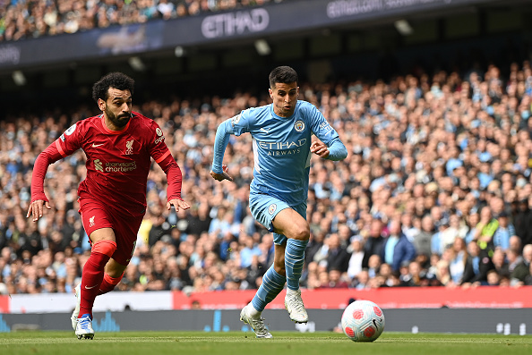 MANCHESTER, ENGLAND - APRIL 10: Joao Cancelo of Manchester City is challenged by Mohamed Salah of Liverpool during the Premier League match between Manchester City and Liverpool at Etihad Stadium on April 10, 2022 in Manchester, England. (Photo by Shaun Botterill/Getty Images)