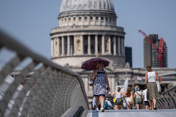 LONDON, ENGLAND - JULY 18: A woman shelters under an umbrella as she walks near St Paul's Cathedral on July 18, 2022 in London, England. Temperatures were expected to hit 40C in parts of the UK this week, prompting the Met Office to issue its first red extreme heat warning in England, from London and the south-east up to York and Manchester. (Photo by Carl Court/Getty Images)