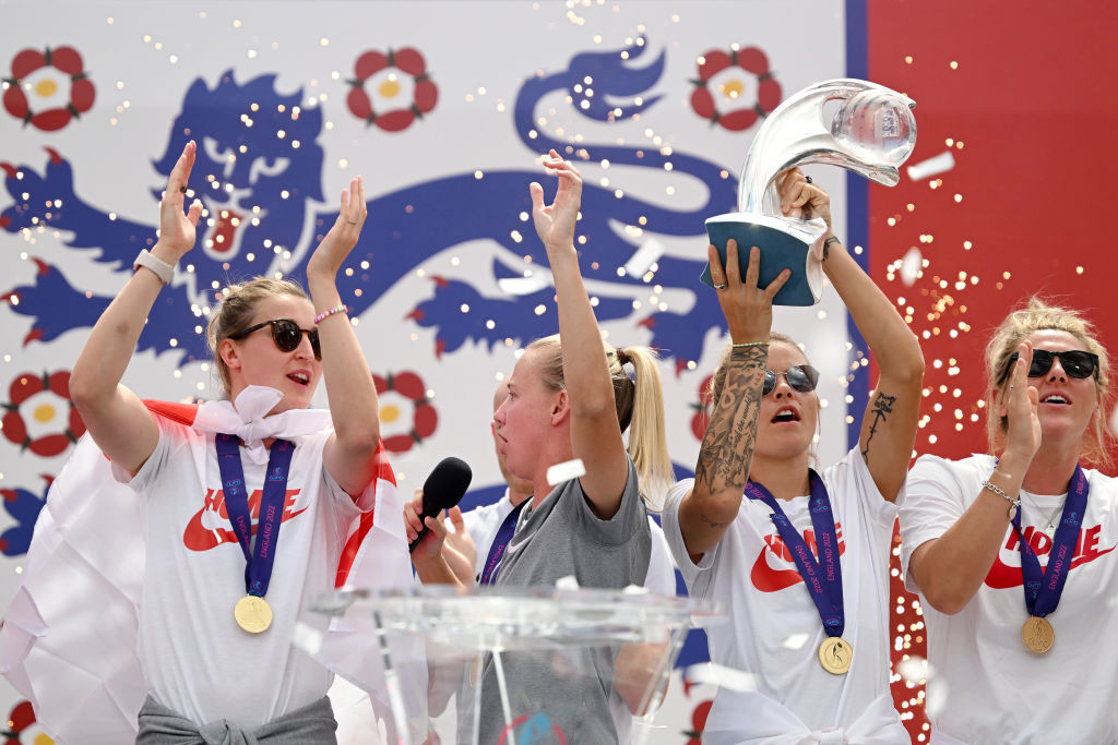 LONDON, ENGLAND - AUGUST 01: (L-R) Ellen White, Beth Mead, Rachel Daly and Millie Bright of England celebrate on stage with the UEFA Women’s EURO 2022 Trophy during the England Women's Team Celebration at Trafalgar Square on August 01, 2022 in London, England. The England Women's Football team beat Germany 2-1 in the Final of The UEFA European Women's Championship last night at Wembley Stadium.  (Photo by Leon Neal/Getty Images)