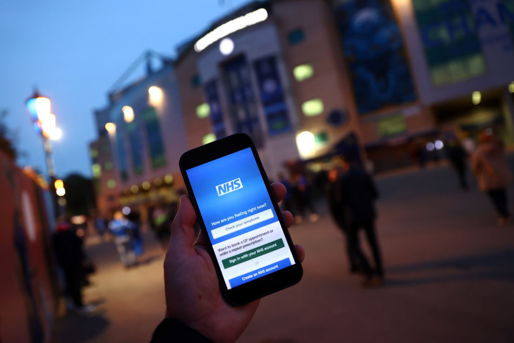 LONDON, ENGLAND - OCTOBER 20: A detailed view of the NHS App on a fans phone as they arrive at the stadium prior to the UEFA Champions League group H match between Chelsea FC and Malmo FF at Stamford Bridge on October 20, 2021 in London, England. (Photo by Clive Rose/Getty Images)