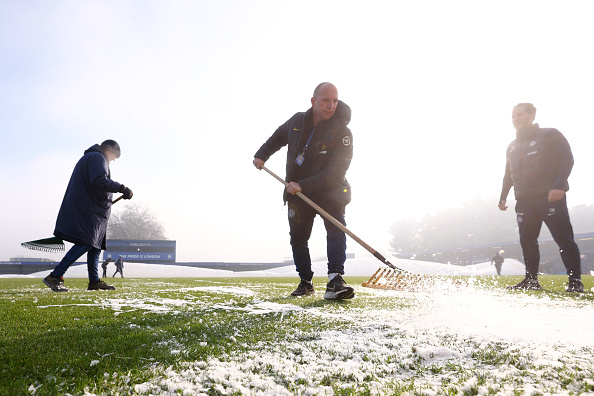 Chelsea grounds staff tried to make the frozen pitch playable for the Women's Super League game by clearing ice and using air blowers