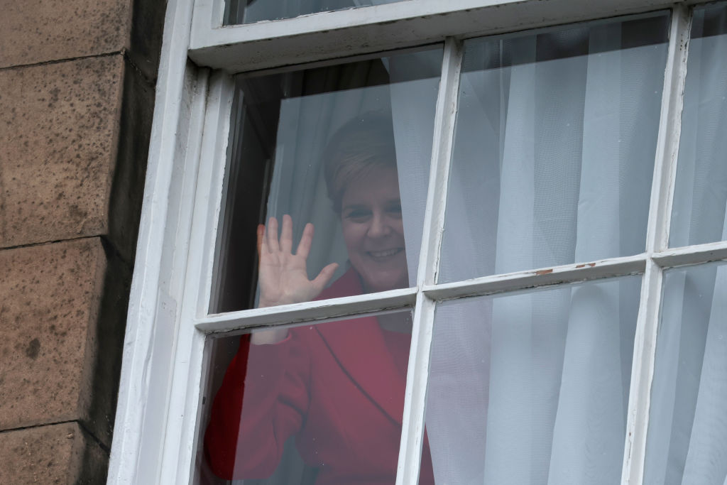 Nicola Sturgeon waves from a window, after holding a press conference  (Photo by Jeff J Mitchell/Getty Images)