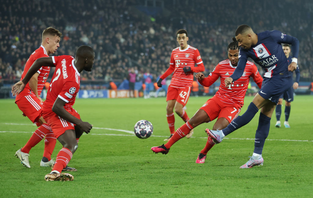 PARIS, FRANCE - FEBRUARY 14: Kylian Mbappe of Paris Saint-Germain has a shot on goal whilst under pressure from players of FC Bayern Munich during the UEFA Champions League round of 16 leg one match between Paris Saint-Germain and FC Bayern Muenchen at Parc des Princes on February 14, 2023 in Paris, France. (Photo by Alex Grimm/Getty Images)