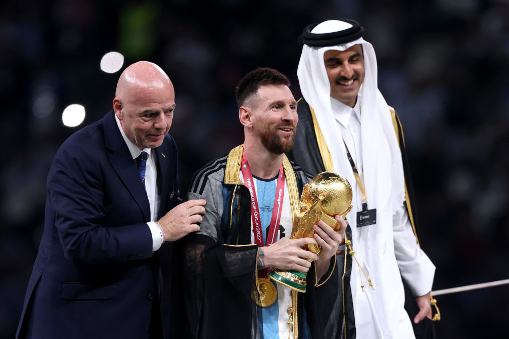 LUSAIL CITY, QATAR - DECEMBER 18: Lionel Messi of Argentina holds the FIFA World Cup Qatar 2022 Winner's Trophy as he interacts with Gianni Infantino, President of FIFA, and Sheikh Tamim bin Hamad Al Thani, Emir of Qatar, during the FIFA World Cup Qatar 2022 Final match between Argentina and France at Lusail Stadium on December 18, 2022 in Lusail City, Qatar. (Photo by Julian Finney/Getty Images)