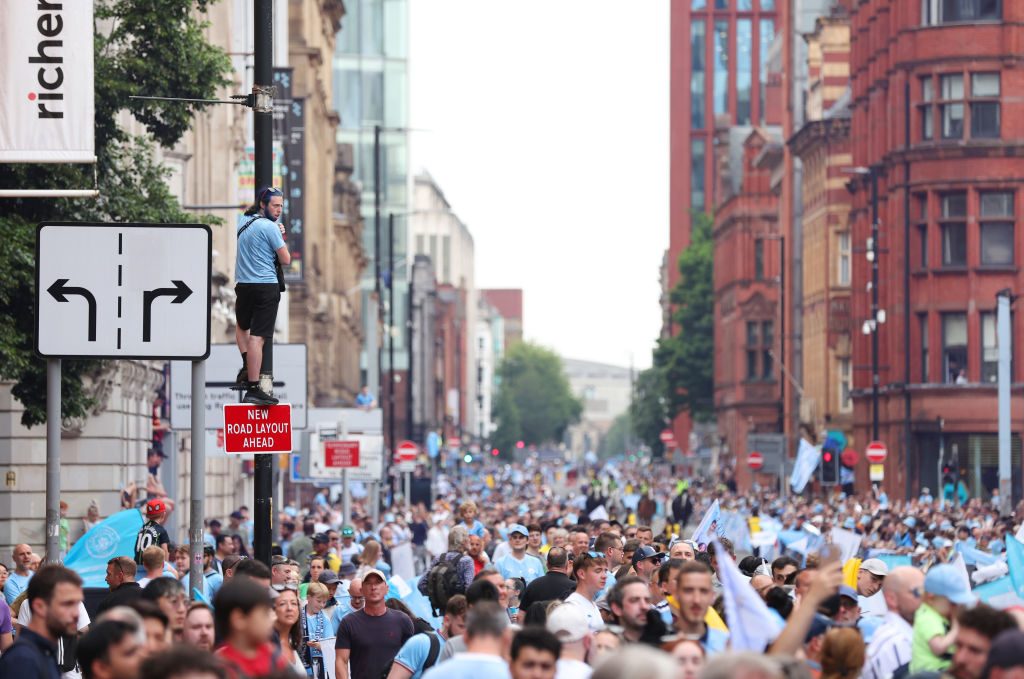MANCHESTER, ENGLAND - JUNE 12: A general view as fans of Manchester City line the street, as a fan climbs a lamp-post, prior to the Manchester City trophy parade on June 12, 2023 in Manchester, England. (Photo by Jan Kruger/Getty Images)