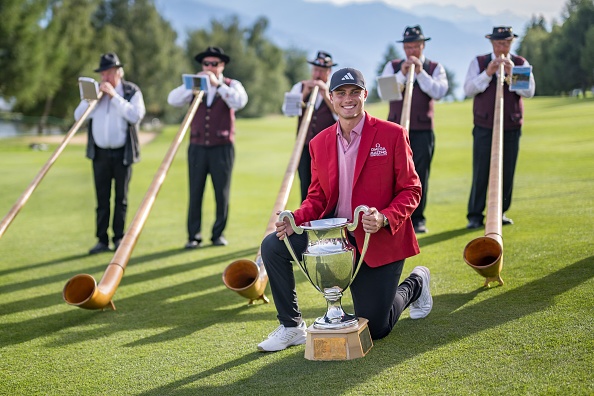 Sweden's Ludvig Aberg poses with the trophy surrounded by alphorn blowers after winning the European Tour's European Masters golf tournament in Crans Montana, western Switzerland on September 3, 2023. (Photo by Fabrice COFFRINI / AFP) (Photo by FABRICE COFFRINI/AFP via Getty Images)