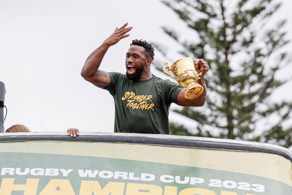TOPSHOT - South Africa's flanker and captain Siya Kolisi reacts as he holds the throphy from the bus carrying the rest of the team during the Springboks Champions trophy tour in East London, South Africa, on November 5, 2023, after South Africa won the France 2023 Rugby World Cup final match against New Zealand. (Photo by WIKUS DE WET / AFP) (Photo by WIKUS DE WET/AFP via Getty Images)