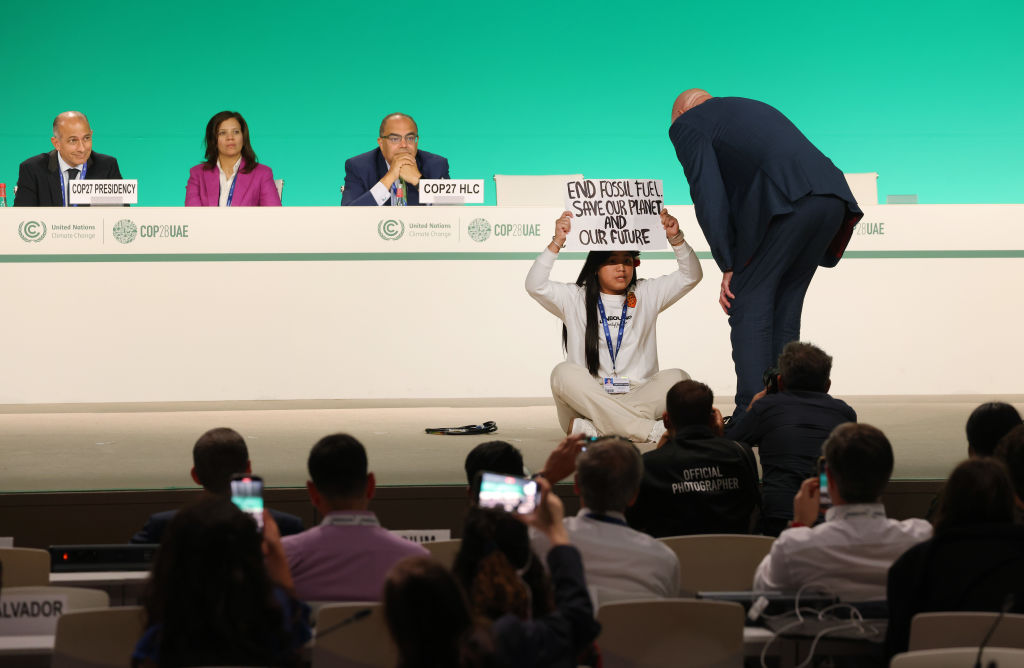 A security guard approaches Indian environmental activist Licypriya Kangujam as she holds up a sign that reads: "End Fossil Fuel. Save Our Planet And Our Future" after she ran onto the stage during a High-Level Event on day eleven of the UNFCCC COP28 Climate Conference as negotiations go into their final phase on December 11, 2023 in Dubai, United Arab Emirates.  . (Photo by Sean Gallup/Getty Images)