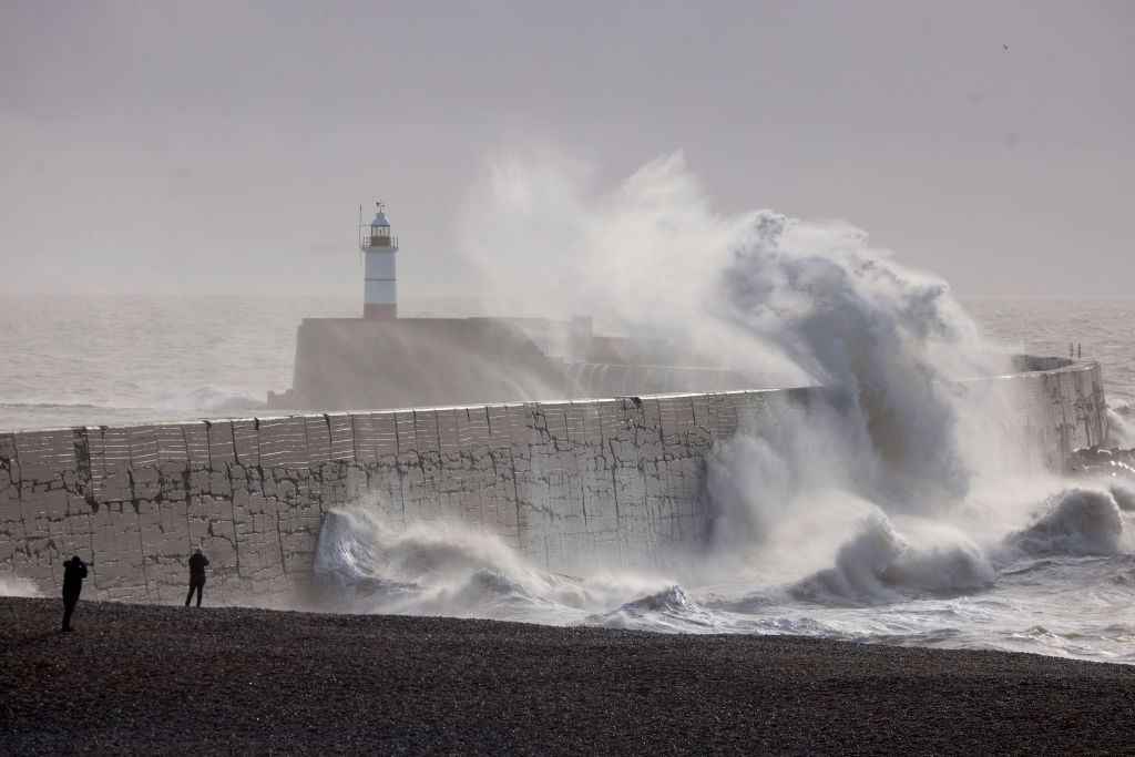 NEWHAVEN, ENGLAND  - JANUARY 22: Waves strike a breakwater, with the Newhaven Lighthouse in the background, on January 22, 2024 in Newhaven, England. Much of the UK was battered overnight by Storm Isha and its high winds, which in some places reached 99mph. (Photo by Dan Kitwood/Getty Images)