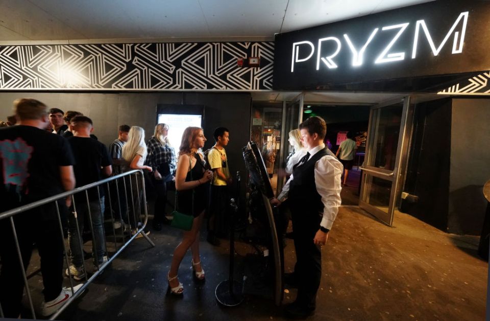 BRIGHTON, ENGLAND - JULY 19: Clubbers queue to have their ID checked, but not their Covid-19 vaccination status, before entry to Pryzm night club in Brighton - which threw open its doors again at the stroke of midnight on July 19, 2021 in Brighton, England. At a minute past midnight, England dropped most of its remaining Covid-19 social restrictions, such as those requiring indoor mask-wearing and limits on group gatherings. These changes come despite rising infections, pitting the country's vaccination programme against the virus's more contagious Delta variant. (Photo by Chris Eades/Getty Images)