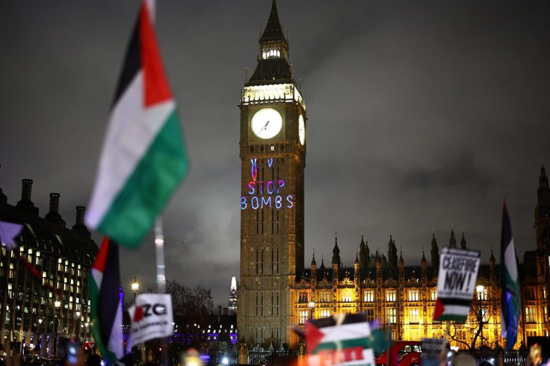A Palestinian flag flaps in the air by a message reading "Stop bombs" projected on The Elizabeth Tower, commonly known by the name of the clock's bell "Big Ben", at the Palace of Westminster, home to the Houses of Parliament, during a Pro-Palestinian demonstration in Parliament Square in London on February 21, 2024, on the sidelines of the Opposition Day motion in the the House of Commons calling for an immediate ceasefire in Gaza. (Photo by HENRY NICHOLLS / AFP) (Photo by HENRY NICHOLLS/AFP via Getty Images)