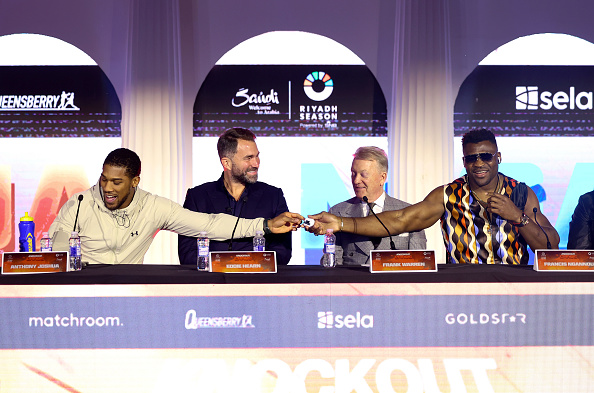 RIYADH, SAUDI ARABIA - MARCH 06: Anthony Joshua passes his Apple AirPods to Francis Ngannou at the press conference ahead of their 'Knockout Chaos' heavyweight fight at Boulevard World on March 06, 2024 in Riyadh, Saudi Arabia. (Photo by Richard Pelham/Getty Images)