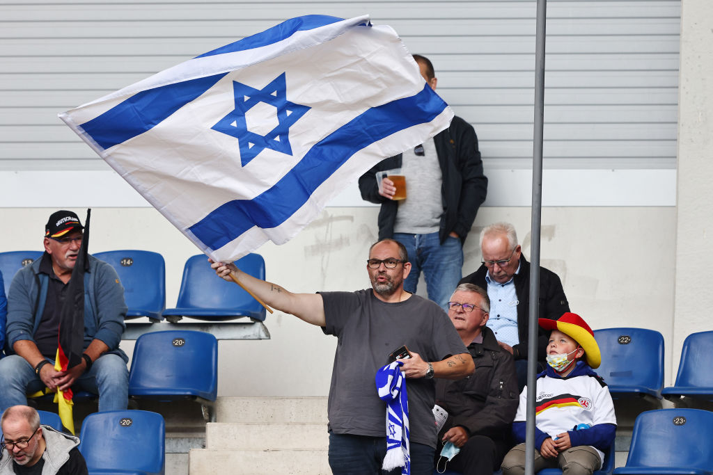 PADERBORN, GERMANY - OCTOBER 07: A fan of Israel waves a flag during the 2022 UEFA European Under-21 Championship Qualifier match between Germany and Israel at Benteler Arena on October 07, 2021 in Paderborn, North Rhine-Westphalia. (Photo by Christof Koepsel/Getty Images)