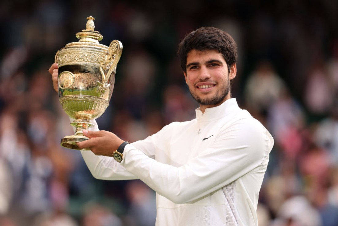 Carlos Alcaraz holds aloft the trophy following his victory in the men's singles final against Novak Djokovic on day fourteen of The Championships Wimbledon 2023 at All England Lawn Tennis and Croquet Club. (Photo by Julian Finney/Getty Images)