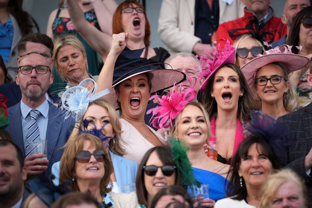 LIVERPOOL, ENGLAND - APRIL 13: Racegoers enjoy the racing and cheer on the hores at Aintree Racecourse on April 13, 2024 in Liverpool, England. One of the highlights of the racing calendar the Grand National is a steeplechase dating back to 1892. It is known the world over and is a race over fences, run for four miles and two-and-a-half furlongs.  (Photo by Christopher Furlong/Getty Images)