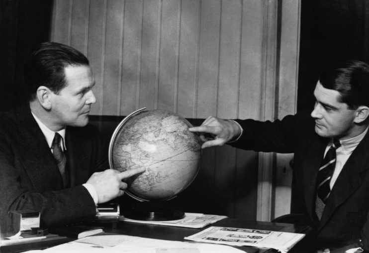 circa 1958: Two men discuss business development with the aid of a globe. (Photo by General Photographic Agency/Getty Images)