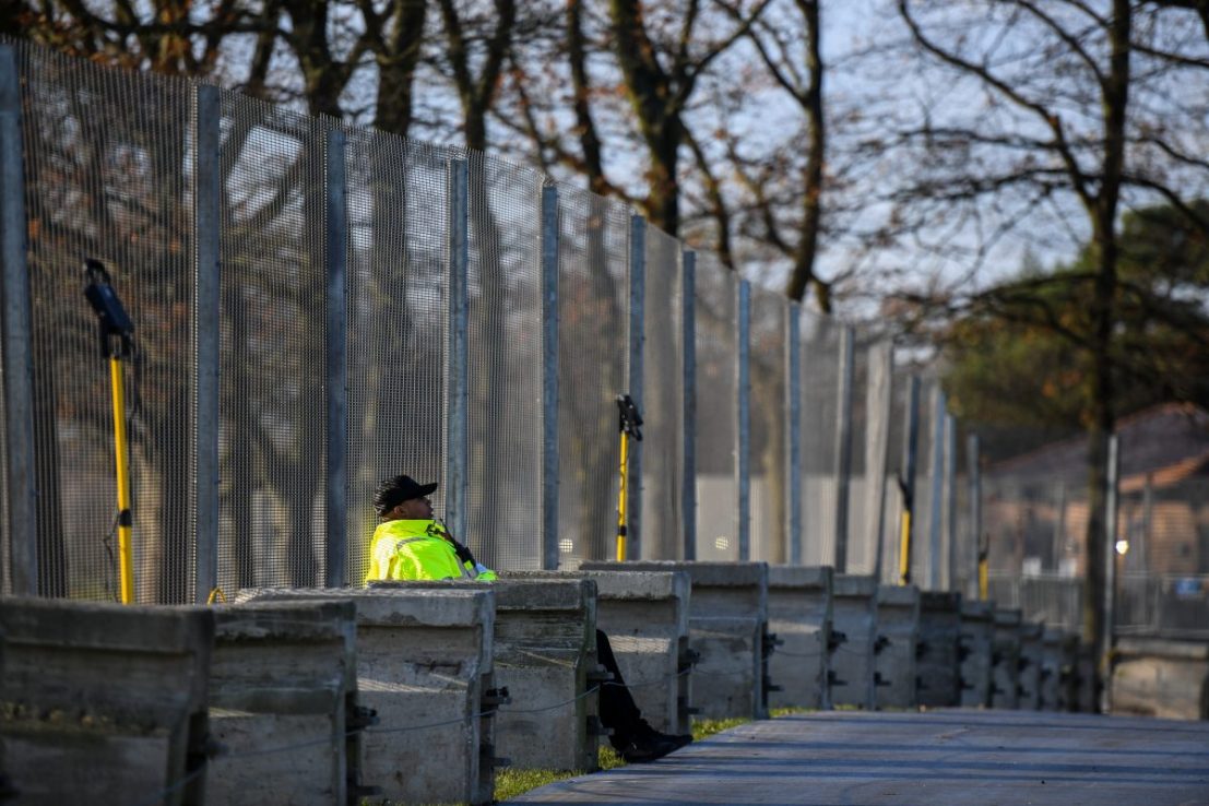 A security guard sits at a perimeter security fence (Photo by Chris J Ratcliffe/Getty Images)