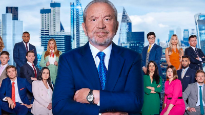 Lord Sugar with Apprentice 2026 cast members in a boardroom setting, featuring modern decor and business attire.