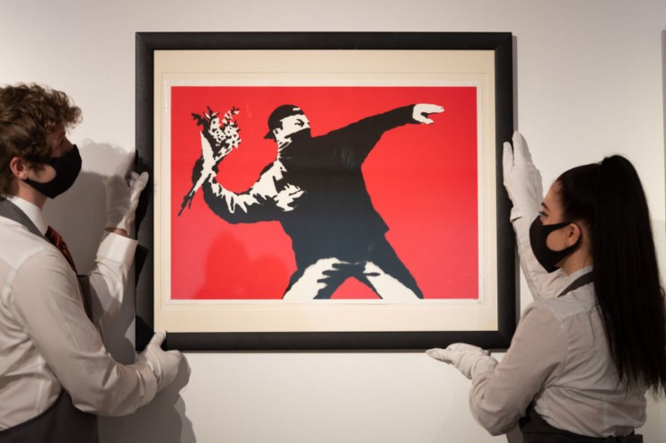 Love is in the Air by Banksy is displayed during preparations ahead of online sales at Christie's Auction House in 2021 in London. (Photo by Ian Gavan/Getty Images)