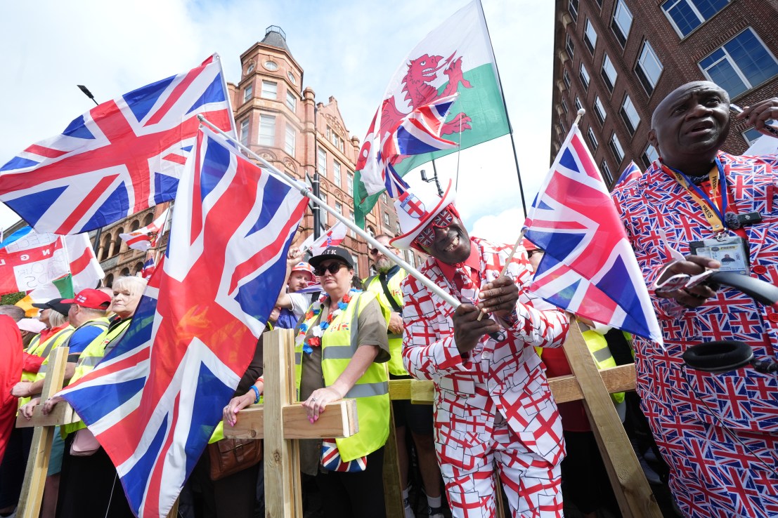 A man wearing a St George Cross suit, surrounded by people holding flags of the UK and Wales, and wooden crosses, during the Tommy Robinson-led Unite the Kingdom march and rally in central London. Picture date: Saturday September 13, 2025. PA Photo. Lucy North/PA Wire