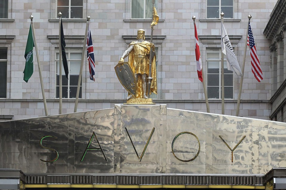 Business professionals in a conference room discussing market strategies with graphs on a large screen in the background